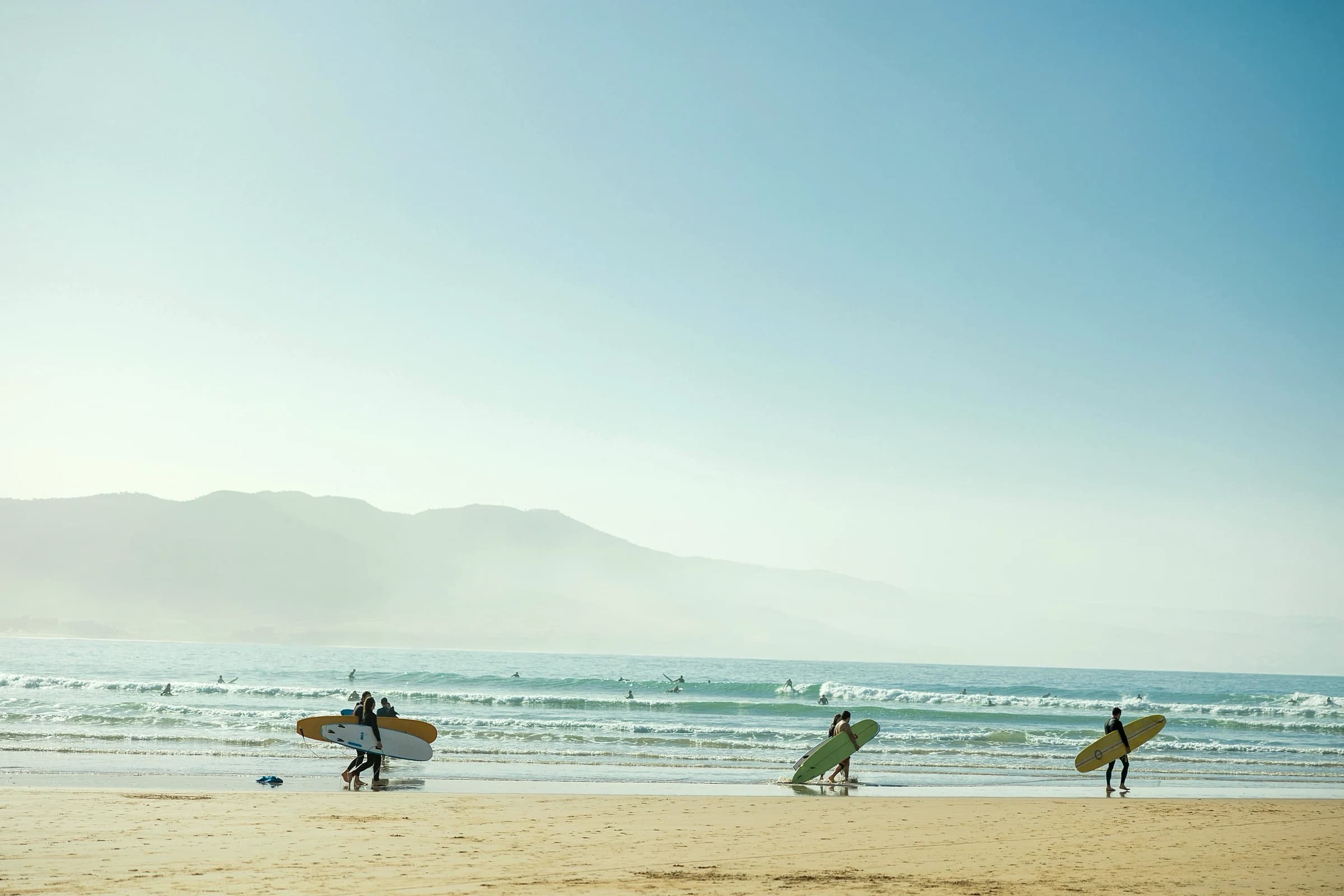 Guests running down the beach to surf at golden hour.